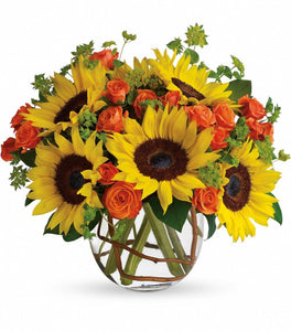 Sunflowers with orange spray roses in clear vase